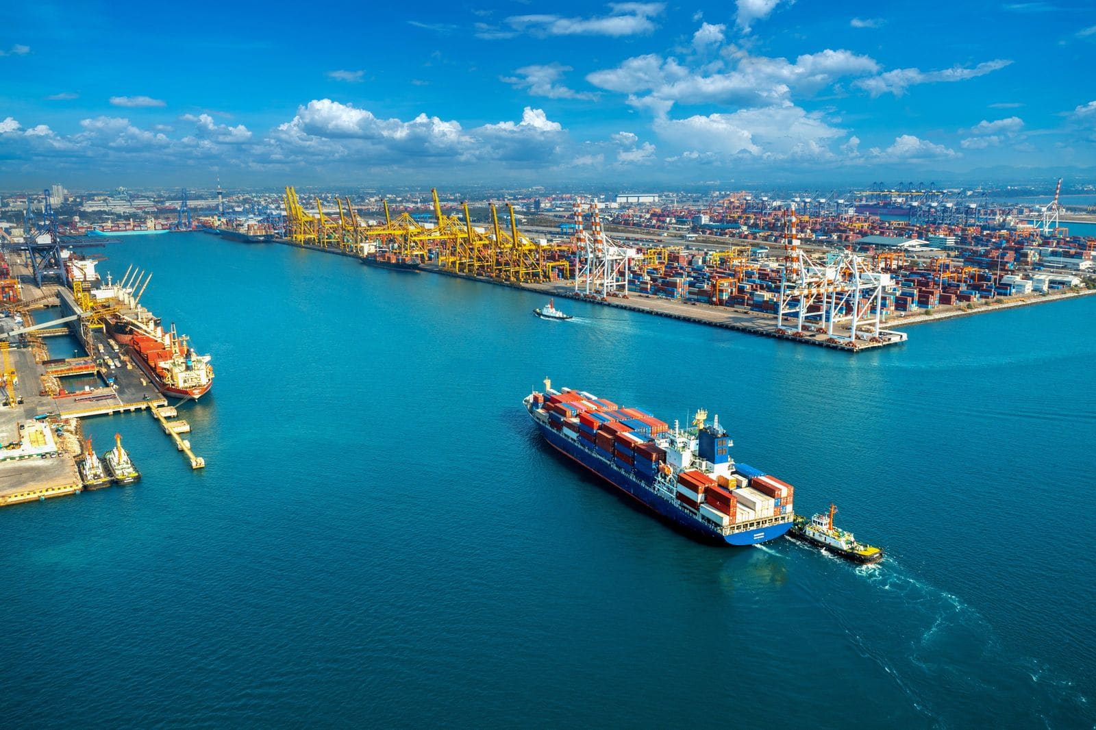 Vista aérea de un puerto de contenedores con un buque de carga entrando al muelle